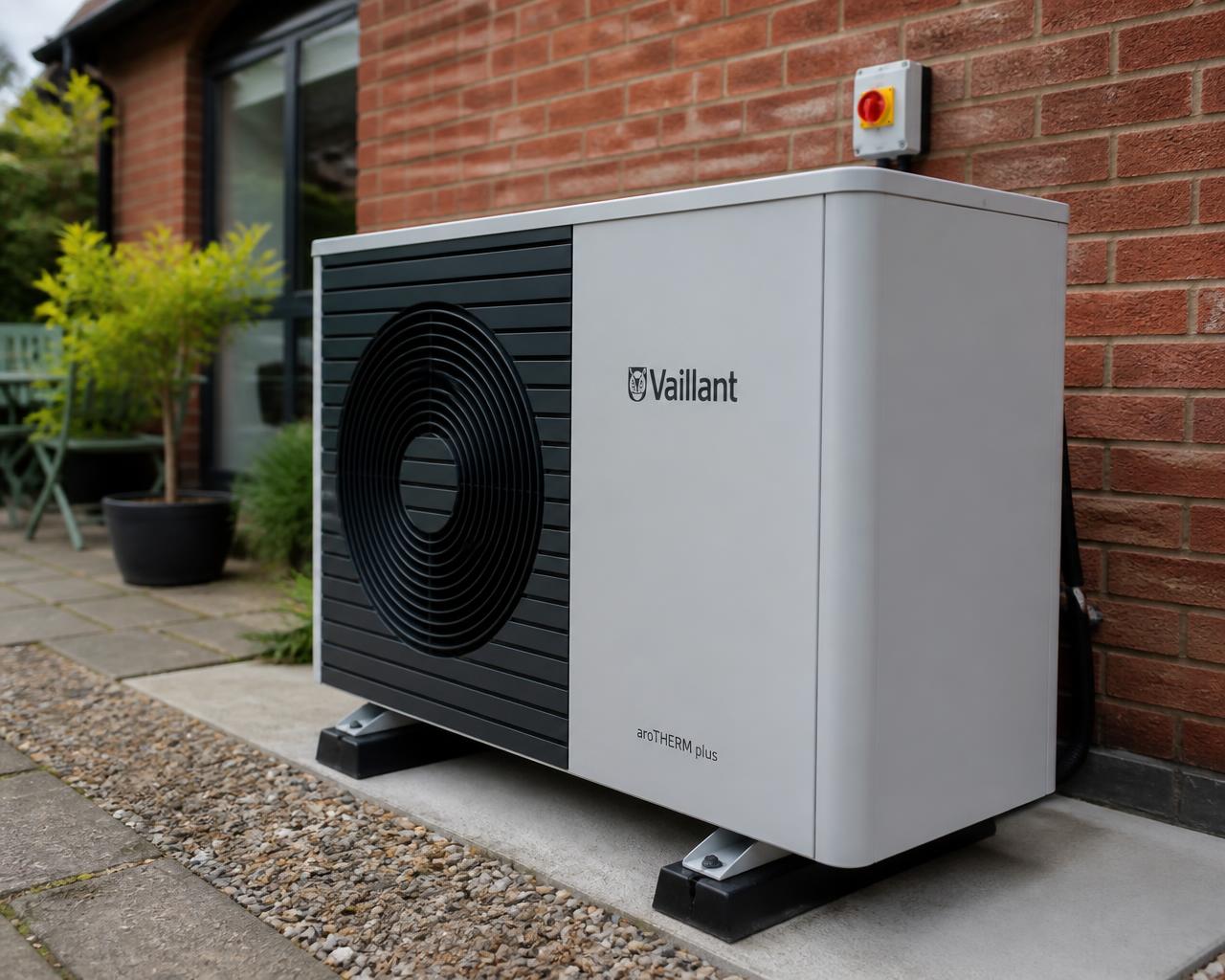 An air source heat pump unit installed against the brick wall of a British home